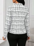 Person wearing a black and white checkered shirt against a neutral background